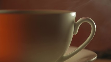 White cup of steaming hot drink on background of coffee beans