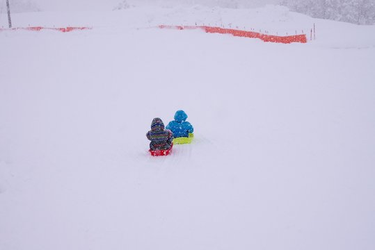雪の降る中そりで遊ぶ子どもたち