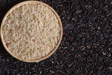 Closeup brown rice in wooden bowl on black berry rice background