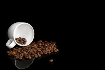 Poured coffee beans with cup on black background.