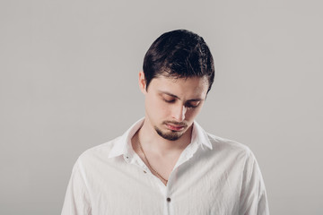 Obraz premium handsome young frustrated and resentful man in white shirt on gr