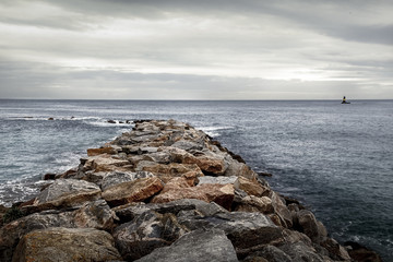 Camino de rocas en el mar y faro en el horizonte