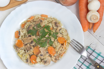Risotto with mushrooms and vegetables in plate on table