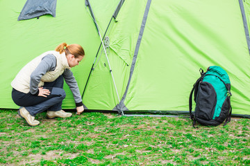 woman hiker setting up tourist tent, during camping vacation