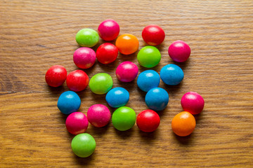 Pile of colorful candy drops on wooden background