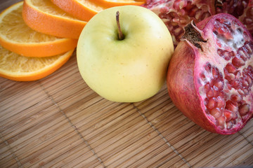 slices of orange and pomegranate on a wooden background