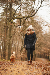 Eine h&uuml;nsche Frau spaziert mit ihrem Hund im Wald