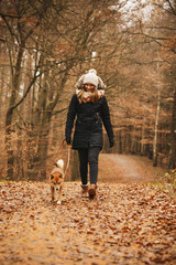 Fototapeta premium Eine hünsche Frau spaziert mit ihrem Hund im Wald