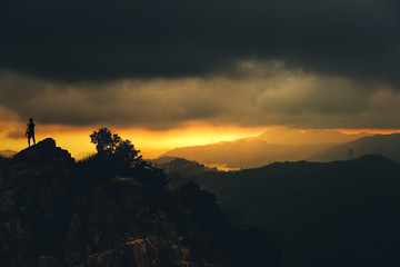 Landscape with silhouette of a standing men take a photo withn phone on lionrock peak in hongkong.