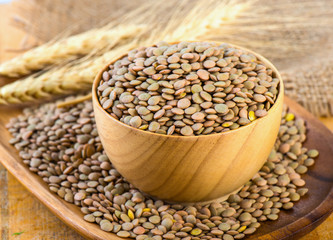 Lentils in a wooden bowl close up on an old table.