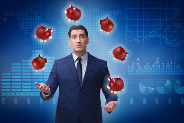 Businessman juggling with piggybanks in business concept