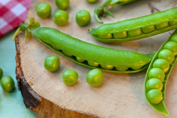 Pods of fresh green peas on wooden board
