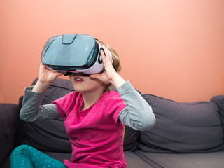 Little Girl on a sofa wearing virtual reality glasses