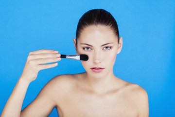 Portrait d'une femme utilisant une brosse de maquillage sur le visage