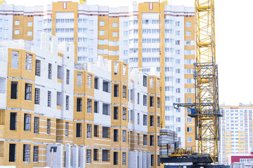 Fototapeta na wymiar Construction of the new complex of residential houses, unfinished process of construction of residential houses. Tower crane and construction material