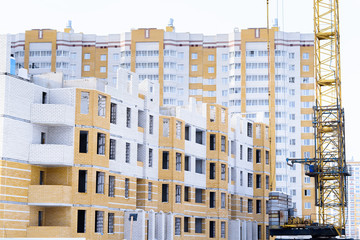 Fototapeta na wymiar Construction of the new complex of residential houses, unfinished process of construction of residential houses. Tower crane and construction material