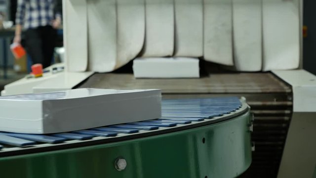 Sealed packs of white paper being transported on the conveyor belt in an Envelope factory