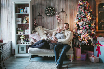 adult couple sitting at the Christmas tree