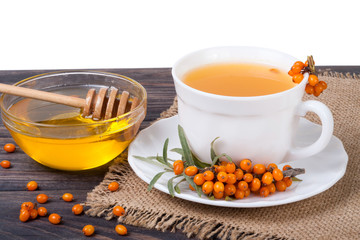 Tea of sea-buckthorn berries with honey on wooden table isolated  white background