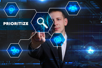 Business, Technology, Internet and network concept. Young businessman working on a virtual blackboard of the future, he sees the inscription: prioritize