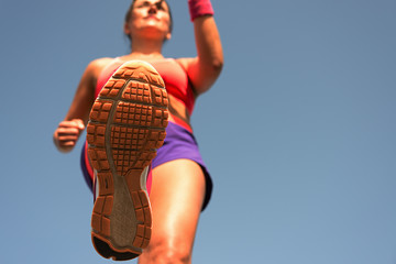 Young woman runner running,training for marathon run.View from below