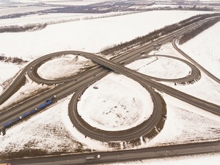 Snowy and frozen winter road with a moving car on it. Aerial view.