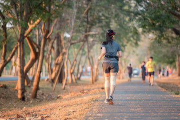 back young woman runner running in tree park during sunset time