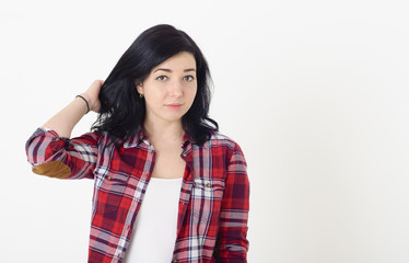 Fototapeta premium Beautiful girl in a red hipster plaid shirt corrects hairstyle t