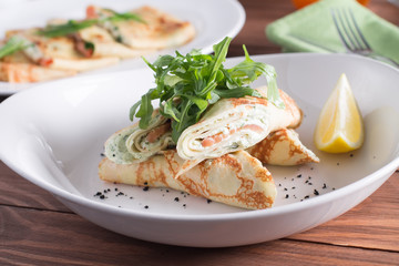 Healthy Breakfast, pancakes with salmon, cheese mousse, herbs, on a wooden table. Selective focus