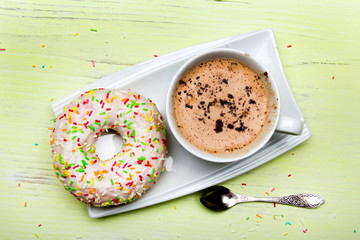 Cup of coffee and tasty donuts with icing and chocolate on green wooden background, copy space