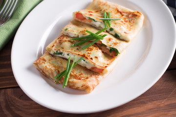 Healthy Breakfast crepes with bacon, cheese, greens, tomatoes on a wooden table. Selective focus