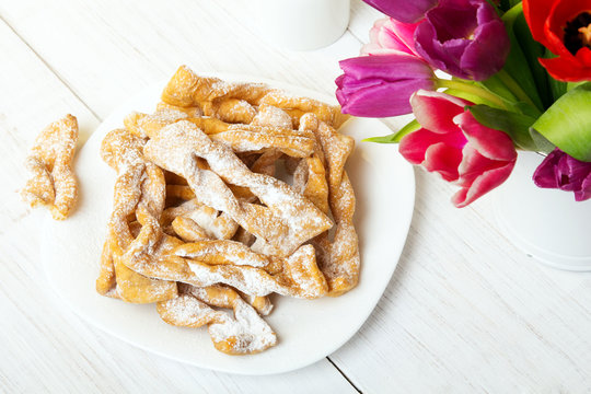 Faworki - Traditional Polish cookies served at Fat Thursday.  Cookies and tulip bouquet on white wooden background