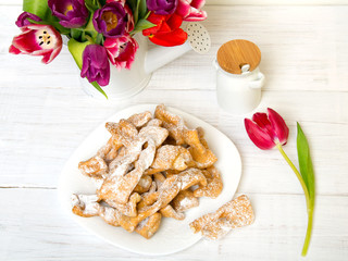 Faworki - Traditional Polish cookies served at Fat Thursday.  Cookies and tulip bouquet on white wooden background