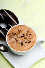 Cup of coffee and tasty donuts with icing and chocolate on green wooden background, copy space