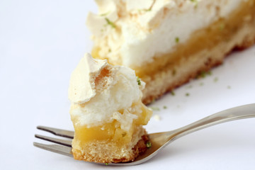 eating bite of piece of lemon meringue pie, tart, decorated with lime, isolated 
