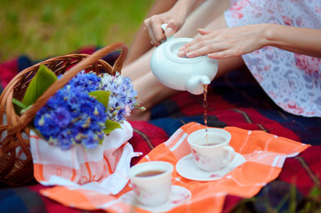 Vintage romantic tea party. Woman pours tea outdoors.