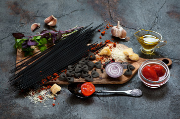 Spaghetti pasta ingredients. Tomatoes, parmesan cheese, garlic, herbs and spices on a gray stone background