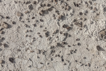 White arid cracked dry textured desert soil with brown black pebbles