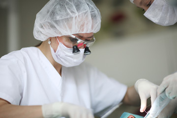 Dentist and assistant are using surgical thread and tools necessary for the manipulation