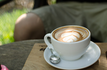 Close up hot Latte Art Coffee in the mug with asia man background.