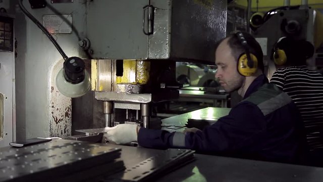 A man working on the machine for punching fasteners