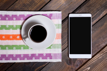 Obraz na płótnie Canvas Coffee in white cup and mobile phone