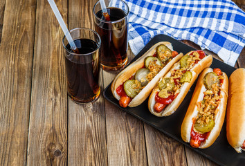 American hot dog with pickles,onions, ketchup, mustard and two soda