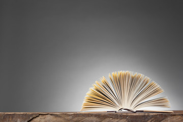 Open Book forming a fan on a wooden Table