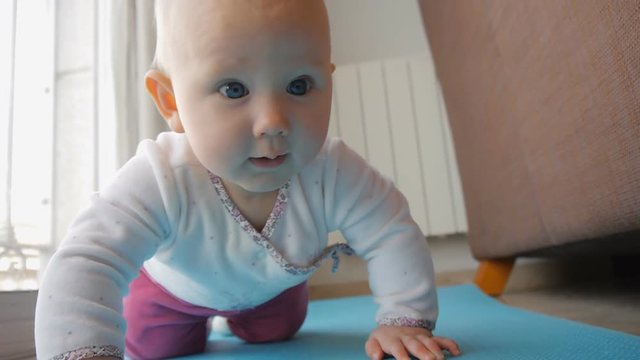 Baby with blue eyes trying to crawl on floor