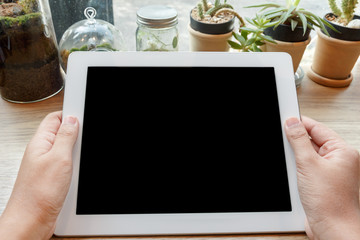 Close up hands holding digital tablet or show screen on wooden desk.