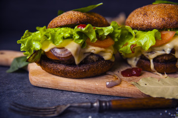 Fast food on the table: burger with beef or pork, or chicken and vegetables, French fries with tomato sauce, basil leaves