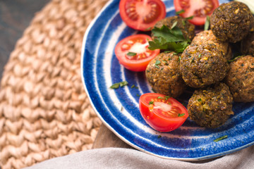 Falafel with tomato and celery on a blue plate on a wicker napkin