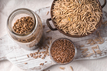 Flax seeds, oats and wheat in the banks on the table