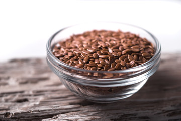 Linen seeds in a glass bowl on wooden table